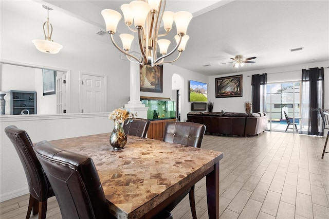 dining room featuring decorative columns, light wood-type flooring, and ceiling fan with notable chandelier