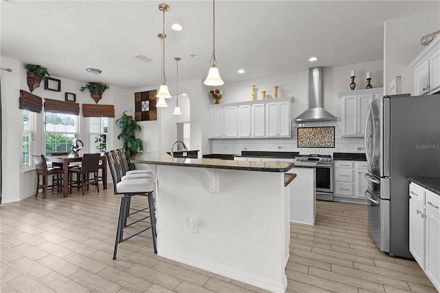 9702 Pepper Tree Pl, Wildwood, FL 34785 - kitchen featuring a breakfast bar area, appliances with stainless steel finishes, wall chimney exhaust hood, and tasteful backsplash