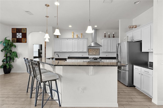9702 Pepper Tree Pl, Wildwood, FL 34785 - kitchen featuring wall chimney exhaust hood, wood tiled floor, backsplash, stainless steel refrigerator with ice dispenser, and visible vents