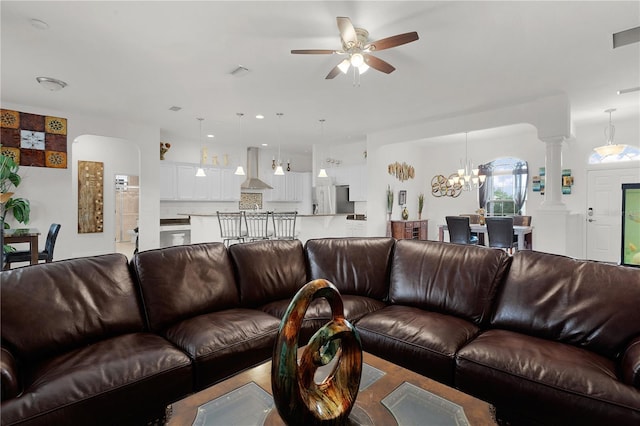 living room with ceiling fan with notable chandelier and ornate columns