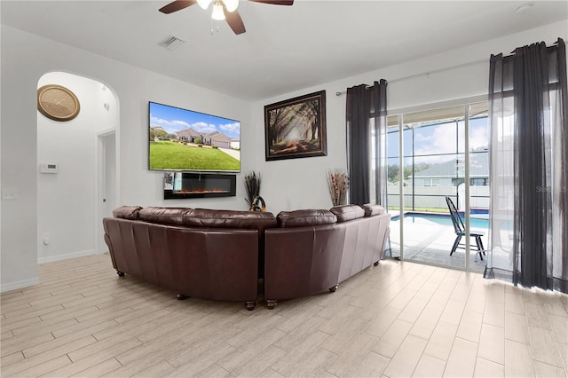 living room featuring light hardwood / wood-style flooring, ceiling fan, and plenty of natural light