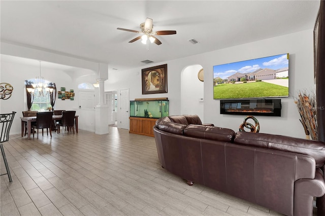 living room with light hardwood / wood-style flooring, decorative columns, a wealth of natural light, and ceiling fan with notable chandelier