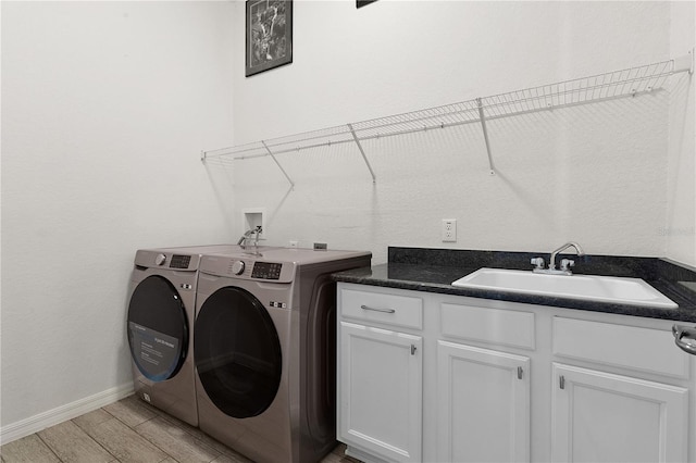 laundry room featuring light hardwood / wood-style flooring, cabinets, sink, and washer and clothes dryer