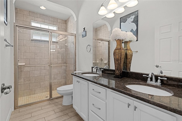 bathroom with toilet, a shower with shower door, and vanity