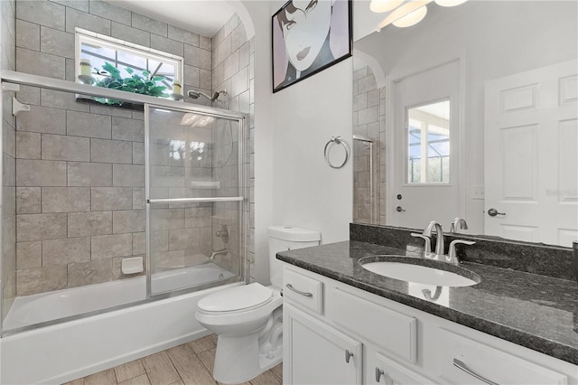 full bathroom featuring vanity, toilet, combined bath / shower with glass door, and wood-type flooring