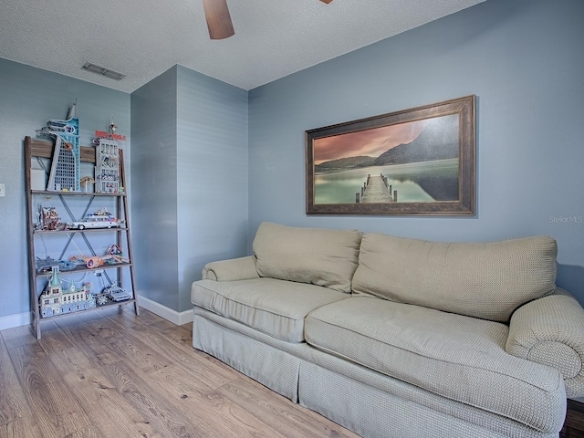 living room featuring a textured ceiling, wood-type flooring, and ceiling fan