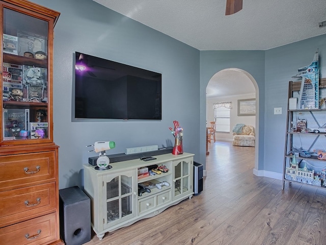 living room featuring ceiling fan, a textured ceiling, and light hardwood / wood-style flooring