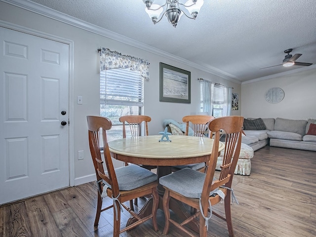 dining room with a textured ceiling, light hardwood / wood-style flooring, plenty of natural light, and ornamental molding