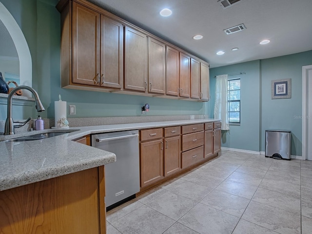 kitchen with light tile patterned floors, light stone countertops, sink, and stainless steel dishwasher