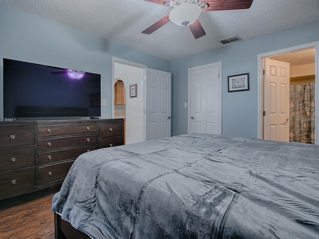 bedroom with connected bathroom, ceiling fan, a textured ceiling, and dark wood-type flooring