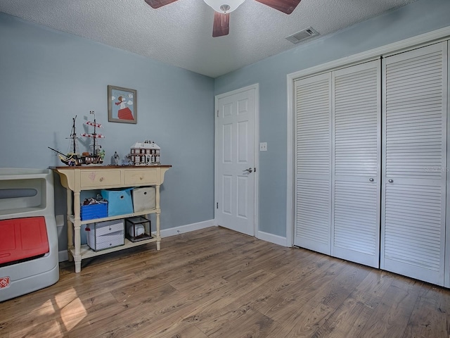 unfurnished bedroom with a textured ceiling, hardwood / wood-style flooring, a closet, and ceiling fan