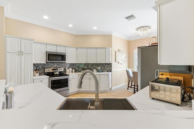 kitchen with white cabinets, stainless steel appliances, light stone countertops, and sink