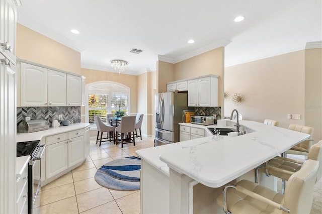 kitchen featuring kitchen peninsula, stainless steel appliances, sink, white cabinets, and a breakfast bar area