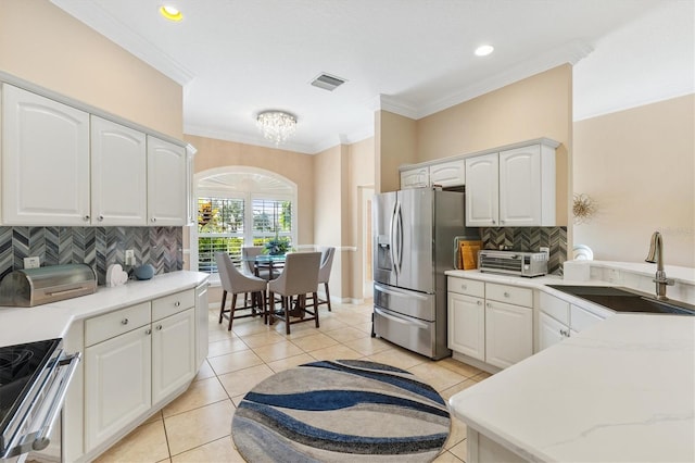 kitchen featuring appliances with stainless steel finishes, tasteful backsplash, ornamental molding, sink, and white cabinets