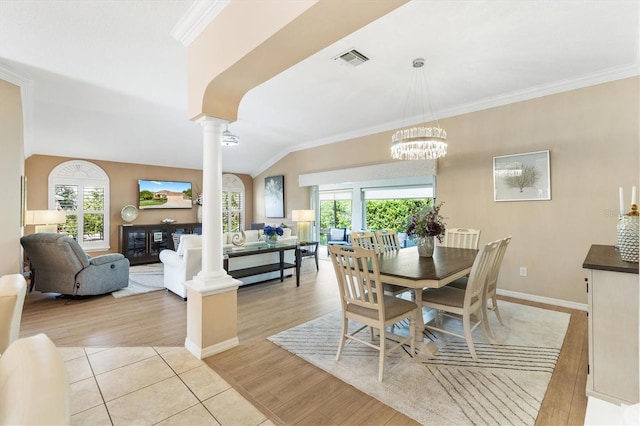 dining room featuring vaulted ceiling, a wealth of natural light, light wood-type flooring, and decorative columns