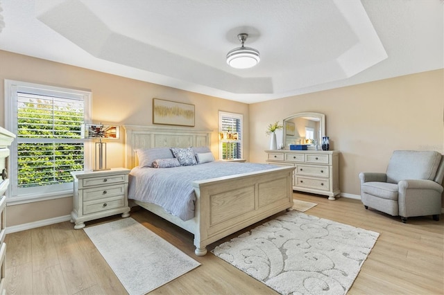 bedroom with a tray ceiling and light hardwood / wood-style flooring