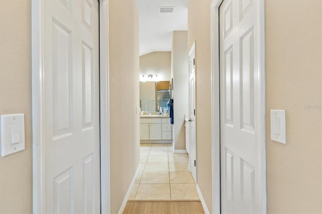 hallway with light tile patterned floors and vaulted ceiling