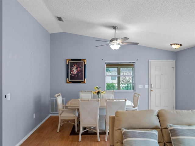 dining room with a textured ceiling, light hardwood / wood-style floors, ceiling fan, and lofted ceiling