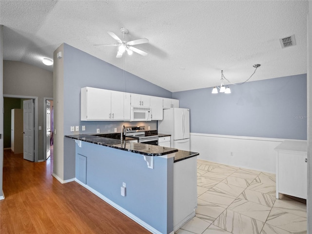 kitchen featuring white appliances, ceiling fan with notable chandelier, kitchen peninsula, dark stone countertops, and white cabinetry