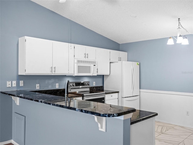 kitchen featuring a textured ceiling, white cabinetry, white appliances, and kitchen peninsula