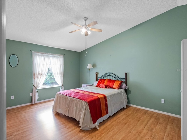 bedroom with a textured ceiling, light hardwood / wood-style flooring, ceiling fan, and lofted ceiling