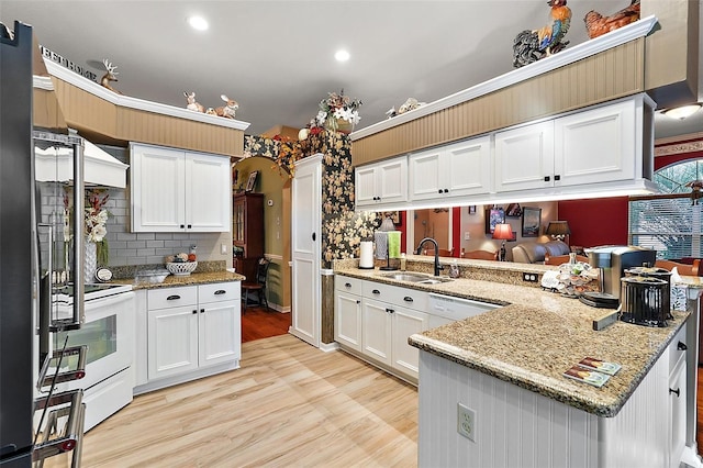 kitchen featuring white appliances, sink, white cabinetry, light hardwood / wood-style floors, and kitchen peninsula