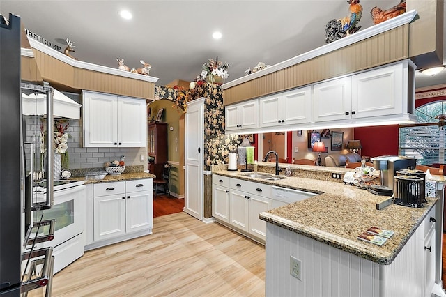 3721 Plantation Blvd, Leesburg, FL 34748 - kitchen with a peninsula, a sink, white appliances, light wood-style floors, and decorative backsplash