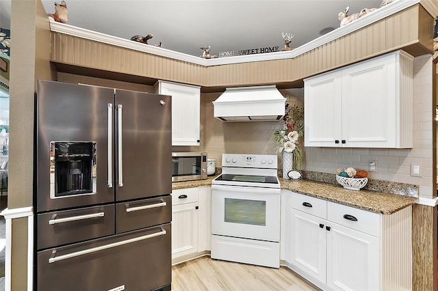 kitchen with white cabinetry, stone counters, appliances with stainless steel finishes, and custom range hood