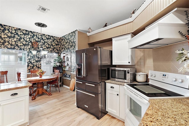 kitchen with high end black fridge, premium range hood, white cabinets, pendant lighting, and electric range