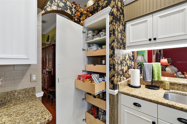 kitchen featuring hardwood / wood-style flooring, light stone countertops, and white cabinets