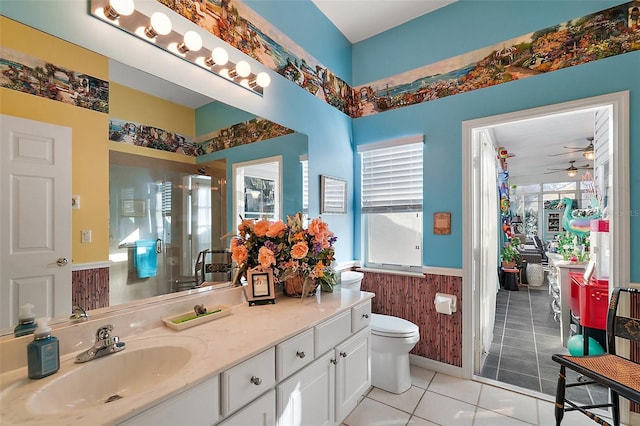 bathroom with tile patterned flooring, wood walls, toilet, ceiling fan, and vanity