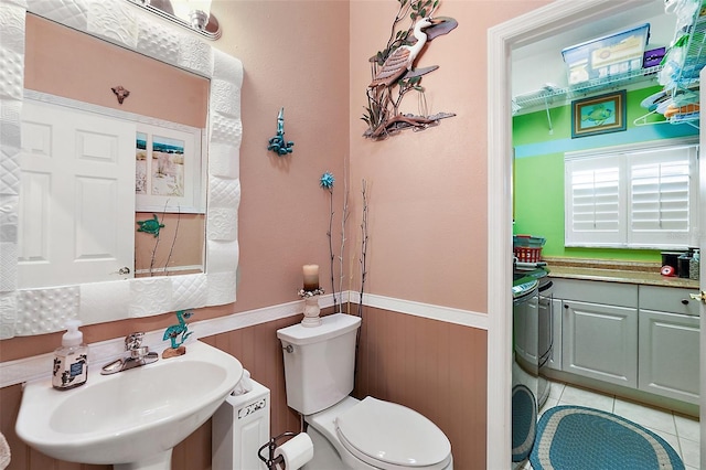 bathroom with sink, toilet, tile patterned flooring, and wooden walls