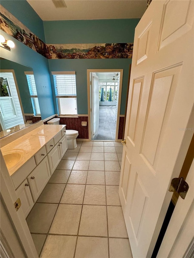 bathroom with toilet, tile patterned floors, vanity, and ceiling fan