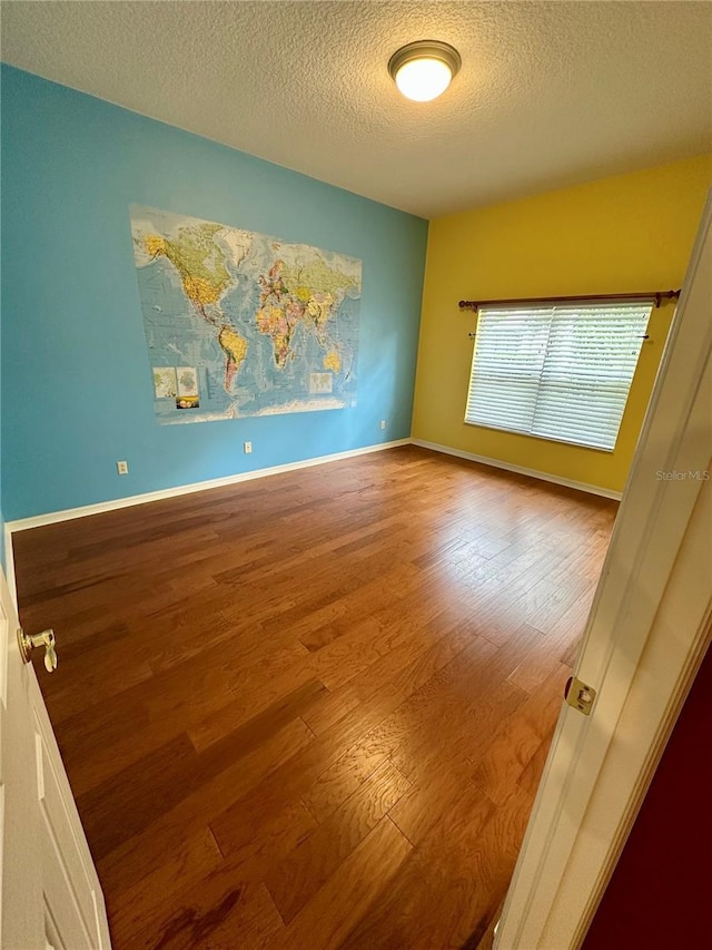 unfurnished room featuring hardwood / wood-style floors and a textured ceiling