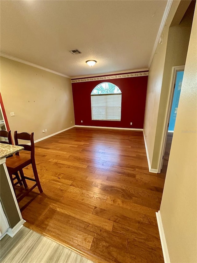 interior space with a textured ceiling, hardwood / wood-style floors, and crown molding