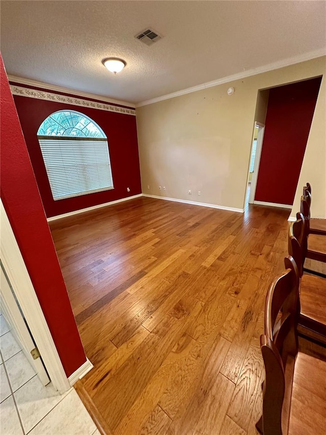 interior space with hardwood / wood-style floors, a textured ceiling, and ornamental molding