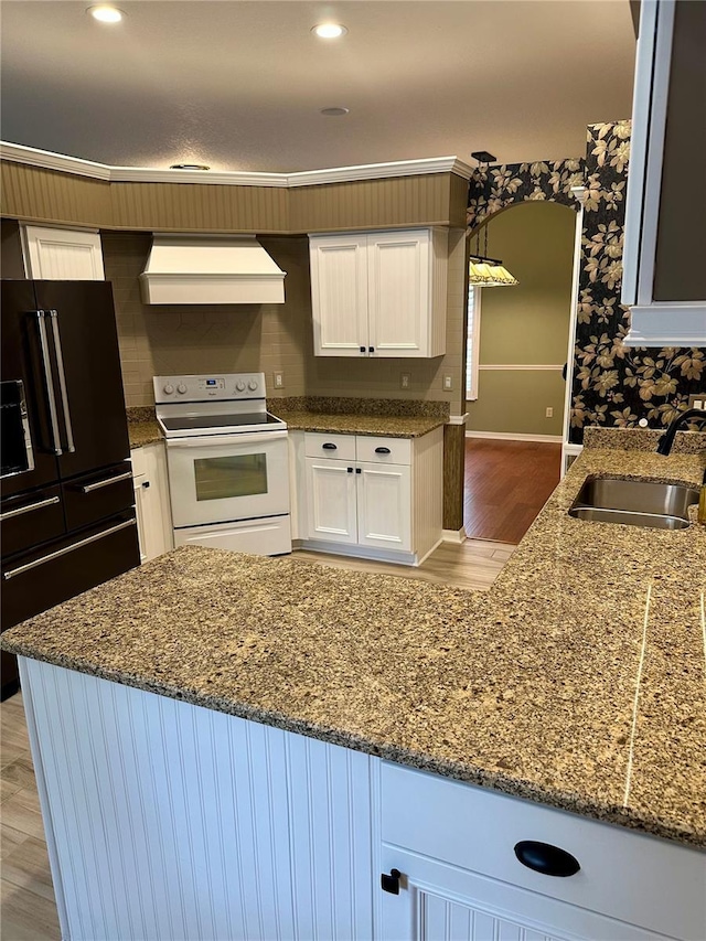 kitchen featuring premium range hood, white electric range, black refrigerator with ice dispenser, sink, and white cabinets