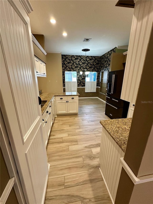 kitchen with light hardwood / wood-style flooring, stone counters, decorative light fixtures, kitchen peninsula, and white cabinets