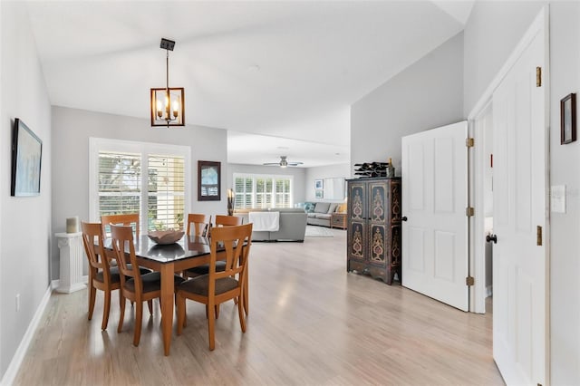 dining area with ceiling fan with notable chandelier and light hardwood / wood-style flooring