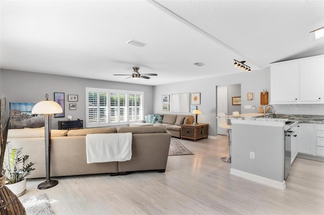 living room featuring light hardwood / wood-style flooring, ceiling fan, and lofted ceiling