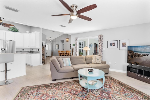 living room featuring ceiling fan, light hardwood / wood-style flooring, and vaulted ceiling