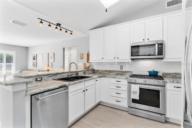 kitchen featuring white cabinetry, sink, kitchen peninsula, vaulted ceiling, and appliances with stainless steel finishes