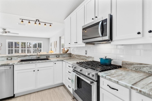 kitchen featuring light stone countertops, sink, appliances with stainless steel finishes, white cabinets, and light wood-type flooring