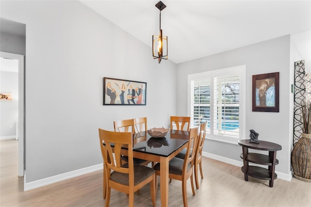 dining area with a notable chandelier, lofted ceiling, and light hardwood / wood-style flooring