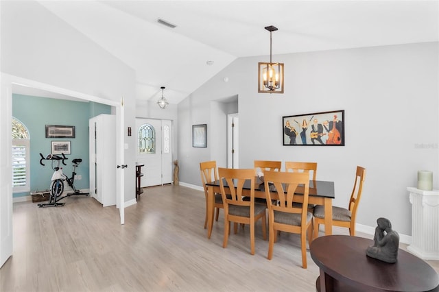 dining room featuring plenty of natural light, an inviting chandelier, high vaulted ceiling, and light wood-type flooring