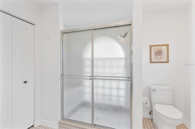 bathroom with tile patterned flooring, toilet, and a shower with shower door