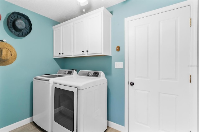 washroom featuring washer and dryer, light hardwood / wood-style floors, cabinets, and a textured ceiling