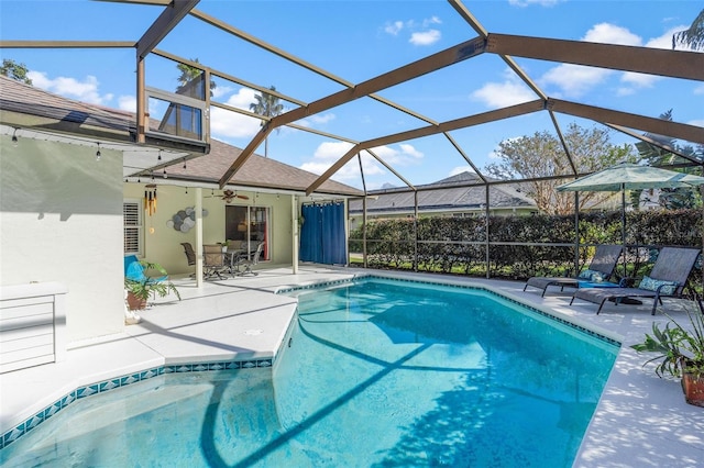 view of swimming pool with glass enclosure, ceiling fan, and a patio