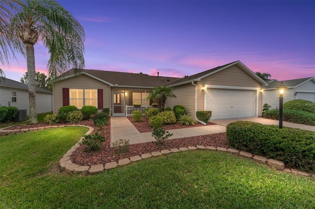 single story home with central AC unit, a garage, and a yard