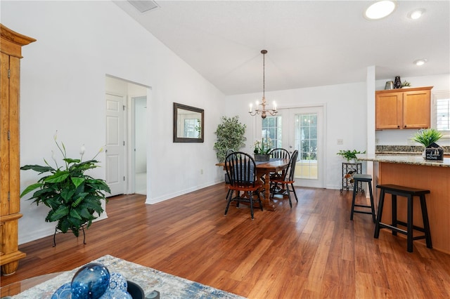 dining space featuring dark wood-type flooring, a chandelier, and lofted ceiling